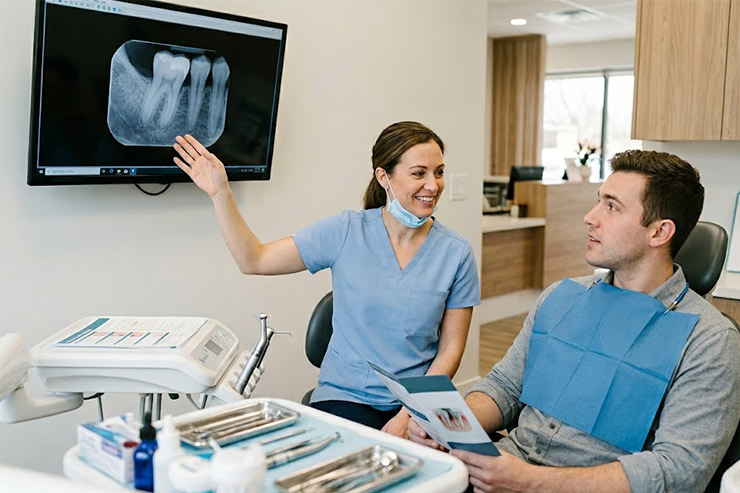 A general dentist is showing a dental X-ray to her patient.
