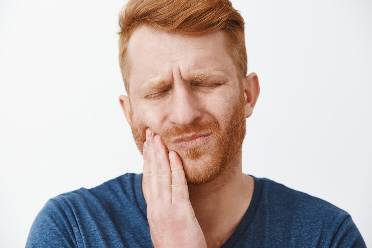 Man holding his cheek in pain from a loose tooth.