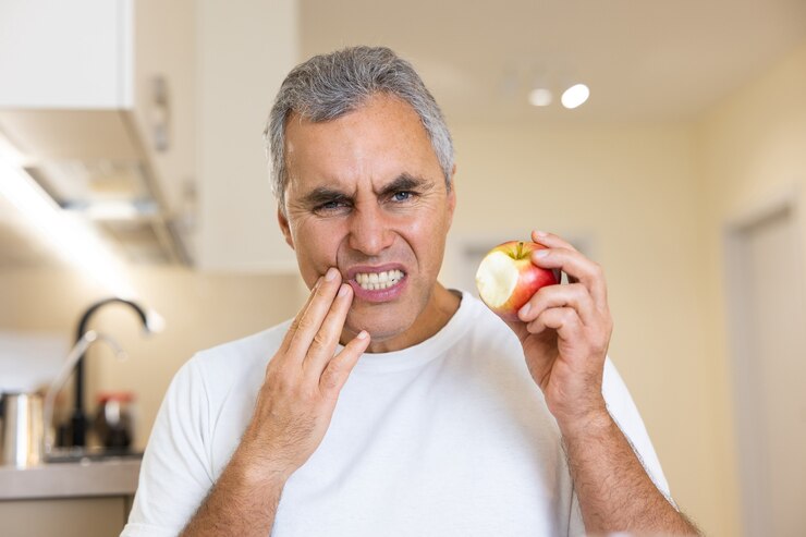 Man with loose tooth biting an apple.